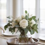 Elegant white rose bouquet in a glass vase on dining table with decorative birds, creating a cozy ambiance.