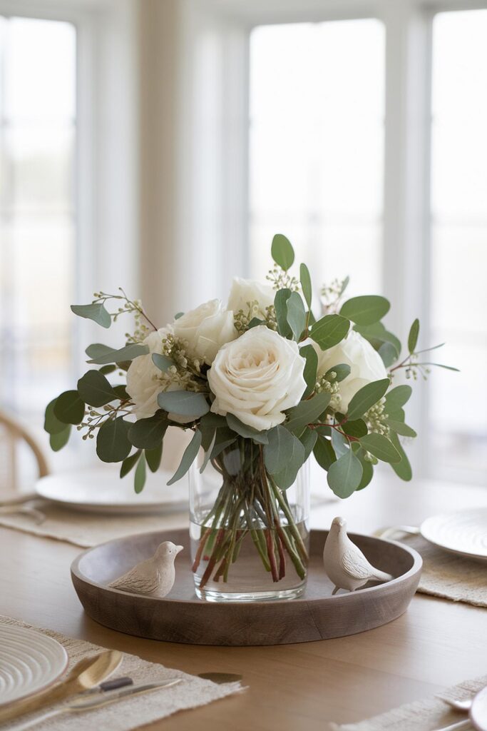 Elegant white rose bouquet in a glass vase on dining table with decorative birds, creating a cozy ambiance.